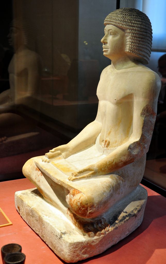 Ancient Egyptian limestone sculpture of a seated scribe at work from the Fifth Dynasty, 2494 to 2345 BC